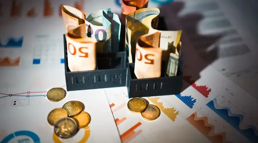 A close-up of euro banknotes and coins on top of financial charts symbolizing investment and economic analysis.