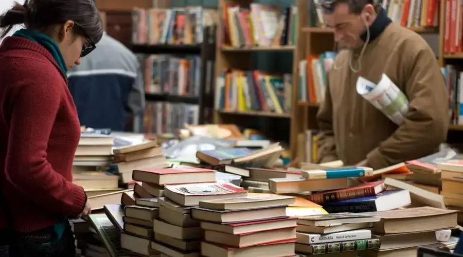 People browsing a large selection of books at a bookstore or market.