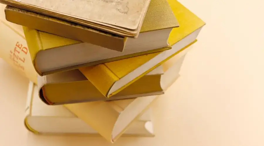 A collection of antique books stacked on a warm cream background, showcasing vintage charm and historical intrigue.