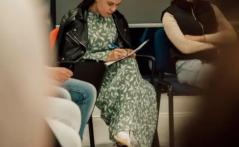 Women taking notes during a meeting indoors, highlighting professional focus.