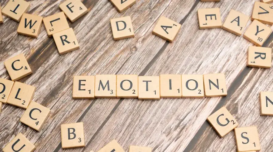 Scrabble tiles forming the word emotion on a wooden background.