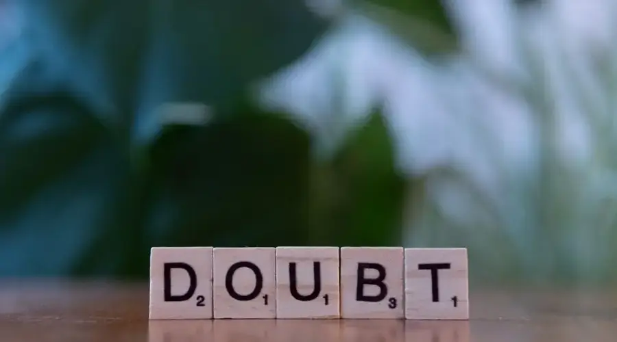 Close-up of Scrabble tiles spelling 'doubt' on a wooden surface, conveying uncertainty.