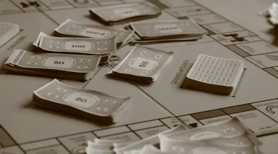 Close-up of board game with play money in sepia tone, focusing on strategic play.