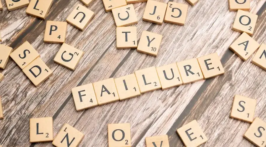 Wooden letter tiles spelling 'failure' on a wooden table, representing challenges.