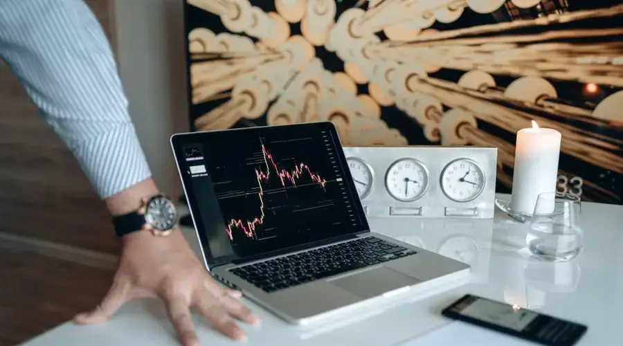 A contemporary desk setting with technology gadgets and a laptop displaying a stock chart.