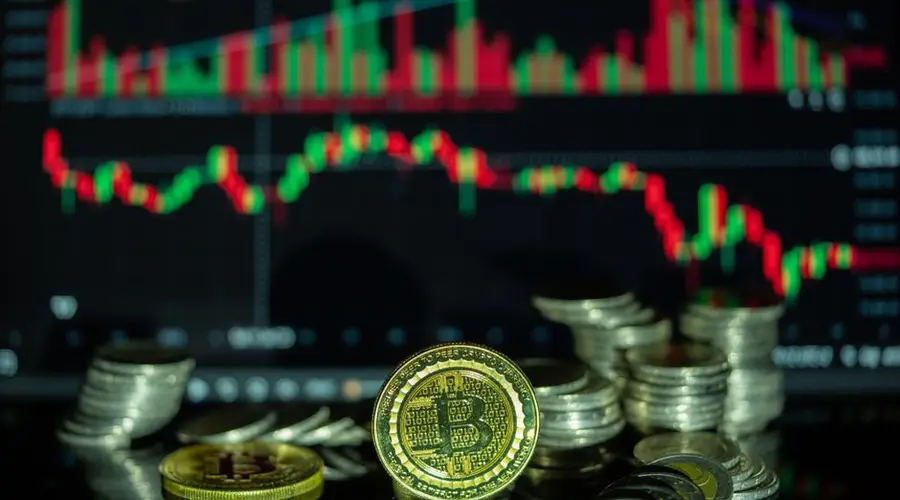 Golden Bitcoin and stacked coins in front of a colorful financial chart, symbolizing cryptocurrency market dynamics.