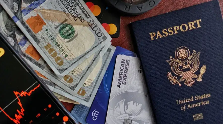 United States passport, cash, credit cards, and smartphone displaying stock market chart.