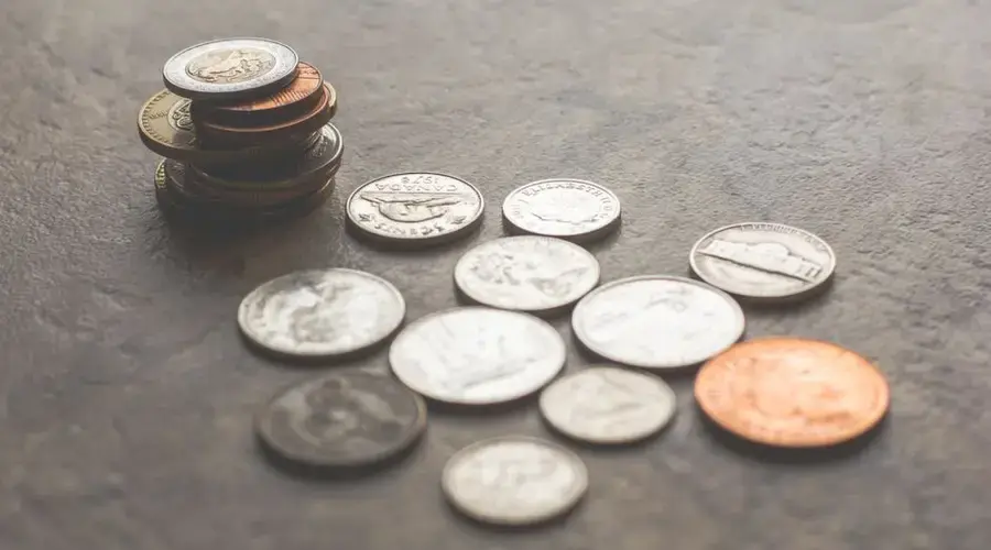 Assorted foreign coins stacked and scattered on a textured surface.