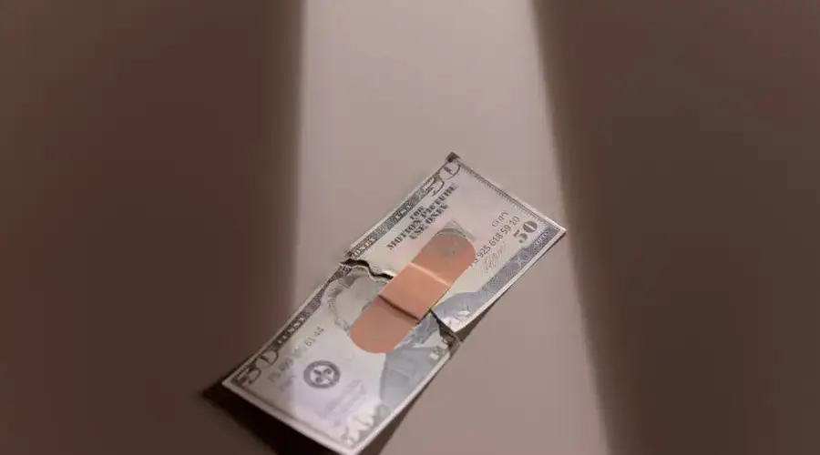 A $50 bill with a bandage symbolizes financial recovery and repair.