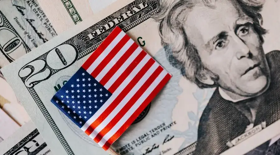 From above of small American flag placed on stack of 20 dollar bills as national currency for business financial operations
