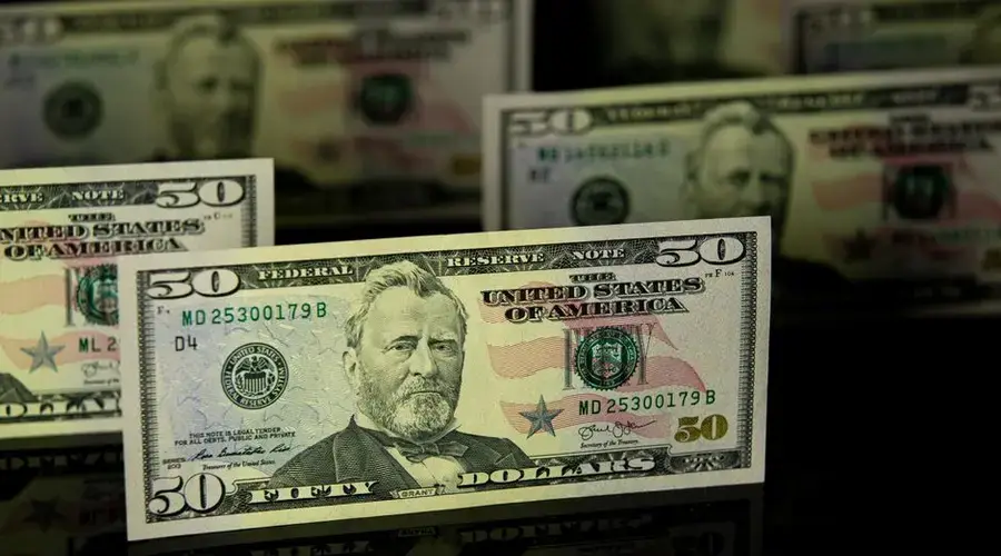Focused shot of fifty dollar bills on a dark reflective surface, highlighting wealth.