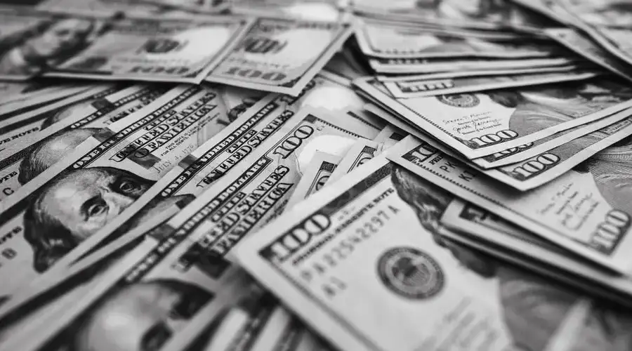 Monochrome image of scattered US hundred dollar bills representing wealth and prosperity.