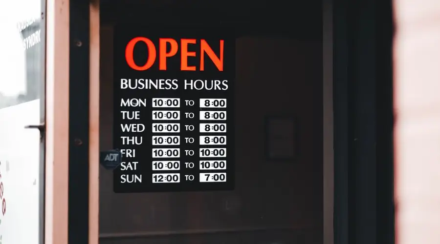 Close-up of an open business hours sign displayed in a shop window.