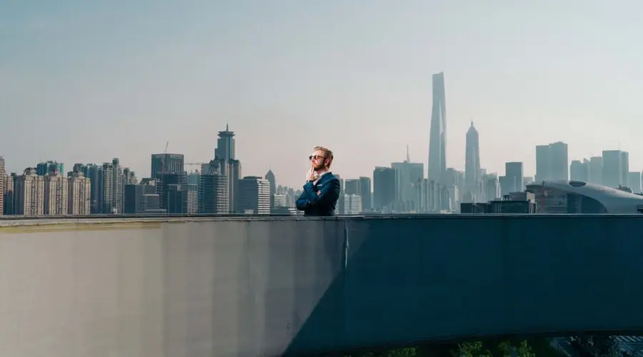 A man stands on a rooftop, gazing over Shanghai's iconic skyline and skyscrapers.