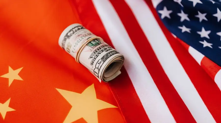 From above of roll of dollar bills tied with rubber band on bright American flag with stars and stripes symbolizing unity and peace