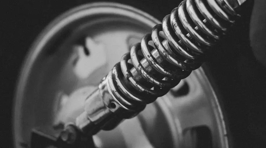Detailed grayscale image of a vehicle suspension spring, highlighting its intricate design.