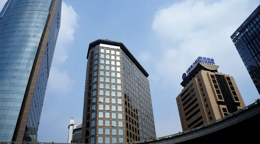Low angle view of skyscrapers against a blue sky in a bustling cityscape.