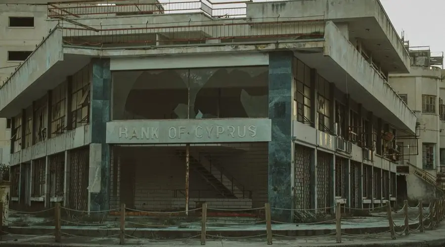 A vintage exterior of an abandoned Bank of Cyprus, with a worn and neglected facade.