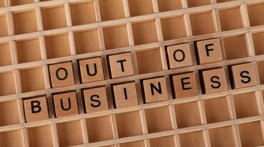 Wooden blocks spelling 'Out of Business', conveying closure or financial difficulties.