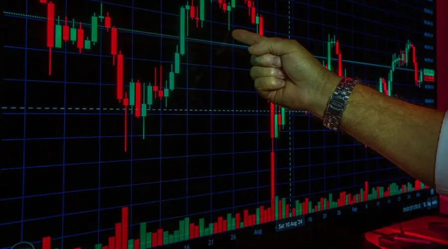 A hand analyzing a financial graph on a digital screen, highlighting stock market trends and data.