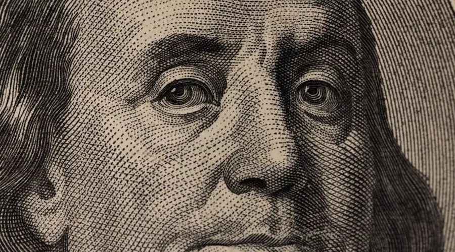Detailed view of Benjamin Franklin's face on a US dollar bill, showcasing fine engraving.