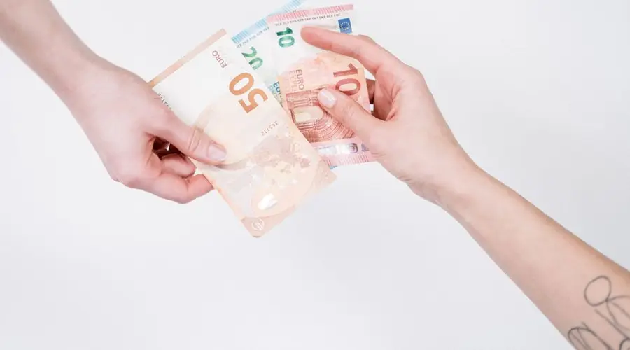 Close-up of hands exchanging euro banknotes, symbolizing financial transactions and currency exchange.