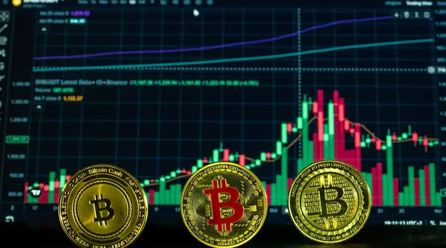 Bitcoin coins in front of a financial graph showing cryptocurrency market analysis.