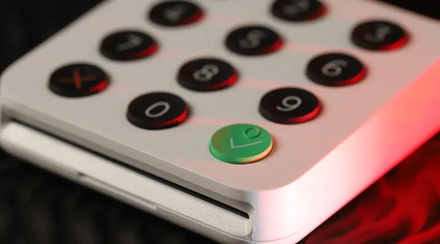 Close-up shot of a digital card reader featuring black and green buttons with numeric keypad.