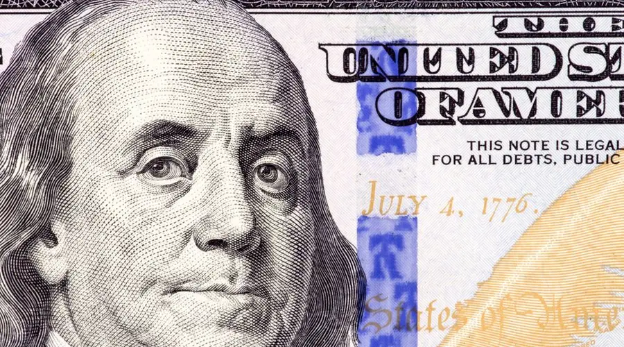 Detailed close-up of Benjamin Franklin's portrait on a 100 dollar bill showing July 4, 1776.