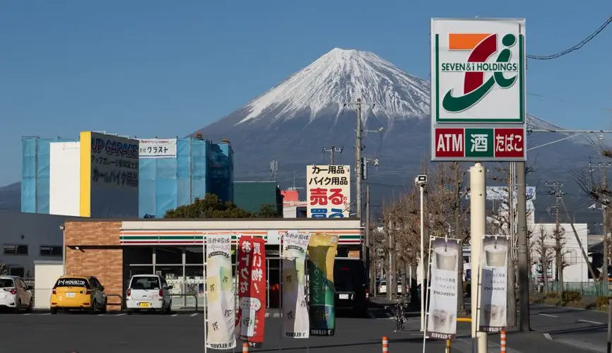 Mount Fuji visible behind a 7-Eleven store sign in Shizuoka, Japan.
