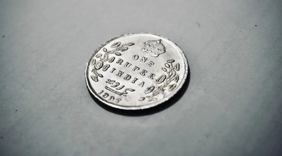 Close-up photograph of a 1907 silver Indian rupee coin with intricate details.