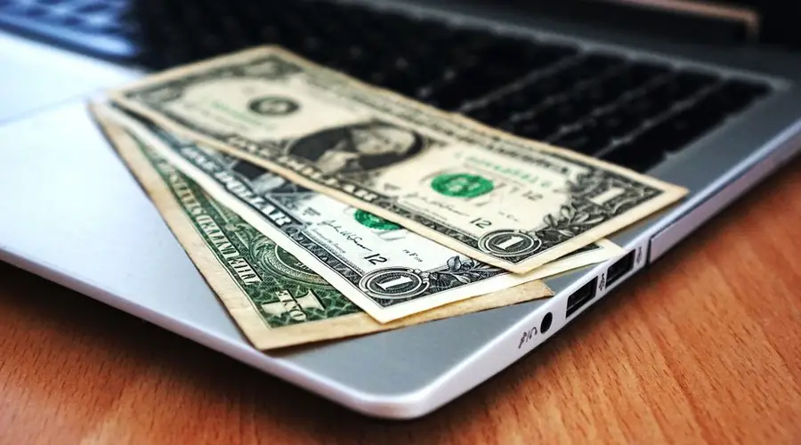 Close-up of US dollar bills placed on a laptop symbolizing digital finance and economy.