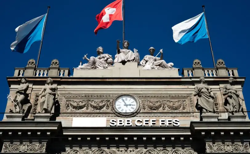 Historic SBB building with Swiss flags and sculptures in Zurich.