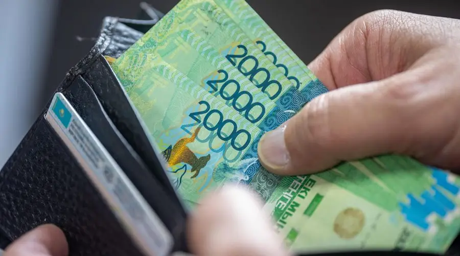 Close-up of hand holding 2000 Kazakhstan Tenge banknotes in a wallet.