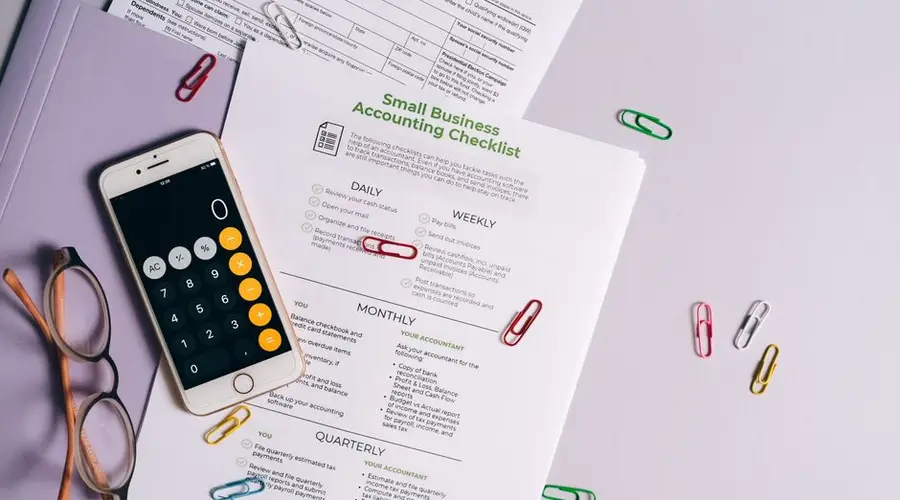 Top view of accounting essentials including smartphone, eyeglasses, and paperwork.