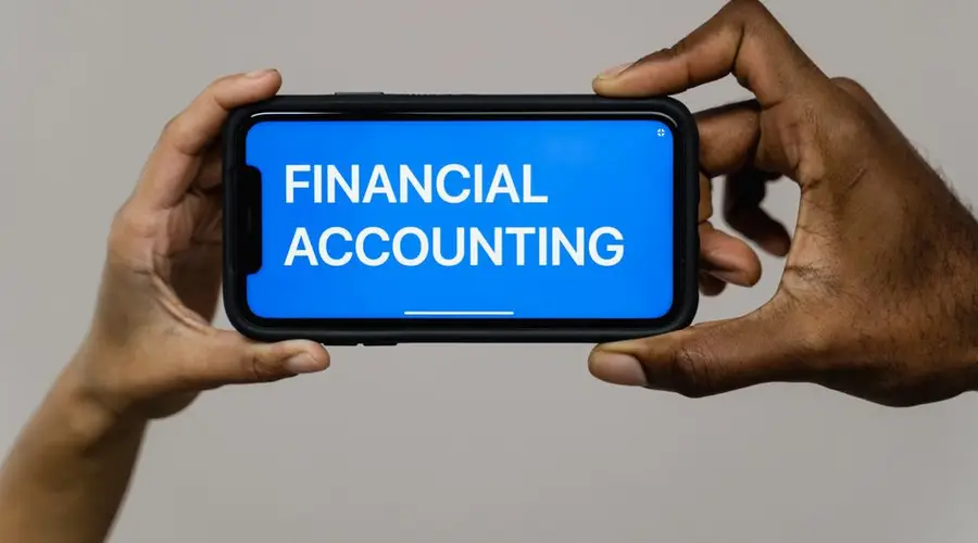 Close-up of hands holding smartphone displaying 'Financial Accounting'.