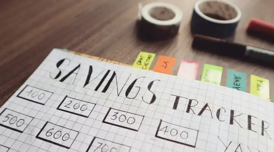 Close-up of a handmade savings tracker with colored tabs on a wooden table, ideal for financial planning visuals.