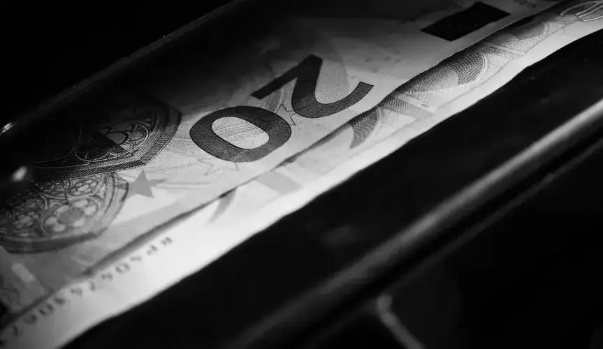Black and white image highlighting a 20 euro bill in a cash register, capturing financial concepts.