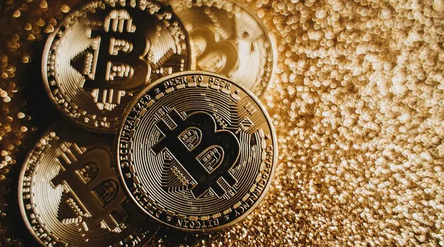 Close-up of Bitcoin cryptocurrency coins on a sparkling gold glitter background, symbolizing digital finance.