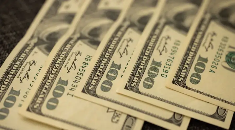 A detailed view of stacked US hundred dollar bills in a close-up shot.