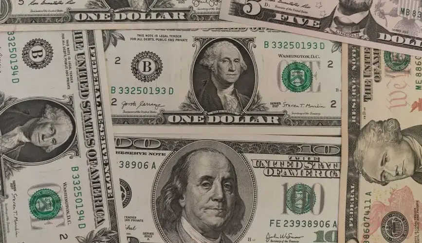 Close-up image showing a mix of U.S. dollar bills including $1, $5, and $10 bills.