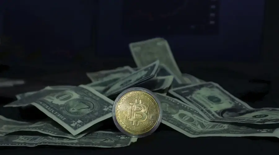 Close-up of a Bitcoin coin and US dollar bills, highlighting cryptocurrency and finance.