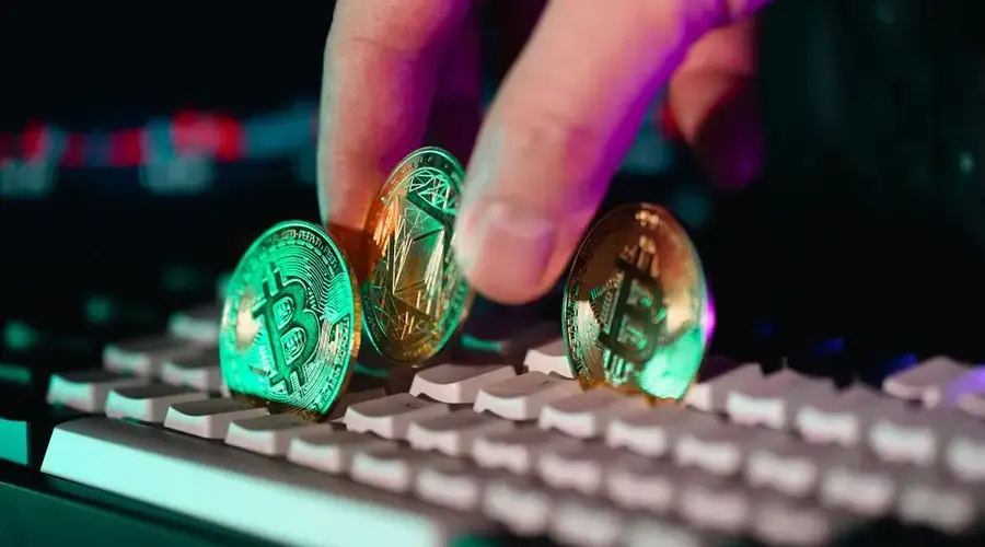 Close-up of cryptocurrency coins on a keyboard with a hand, symbolizing digital currency and finance technology.