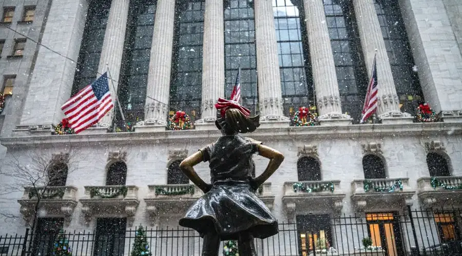 The Fearless Girl statue stands boldly in winter snow at the New York Stock Exchange.