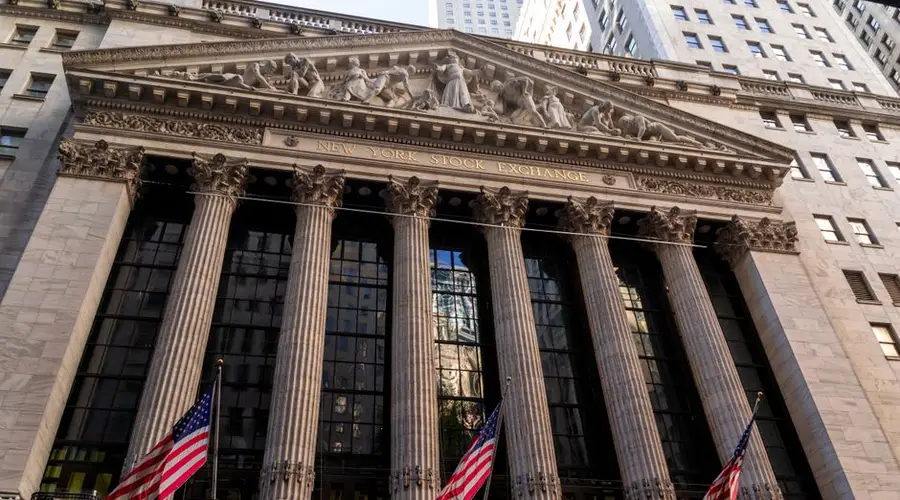 Iconic neoclassical facade of the New York Stock Exchange with American flags.