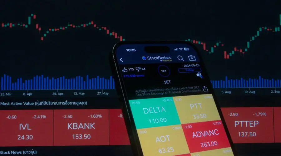 Mobile screen displaying stock trading app with market graphs in background.