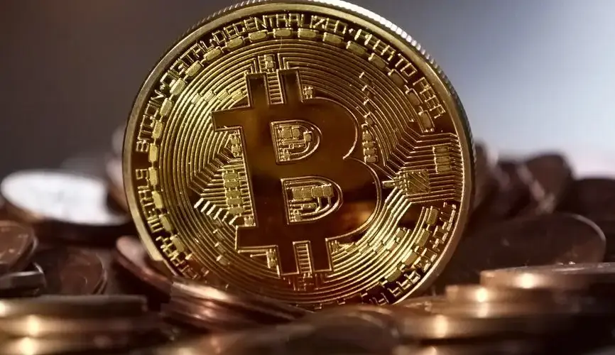 Close-up of a digital cryptocurrency Bitcoin coin placed on a pile of coins.
