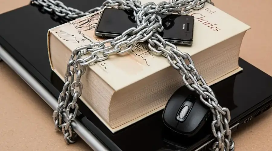 Chain-locked book, phone, and laptop symbolizing digital and intellectual security.