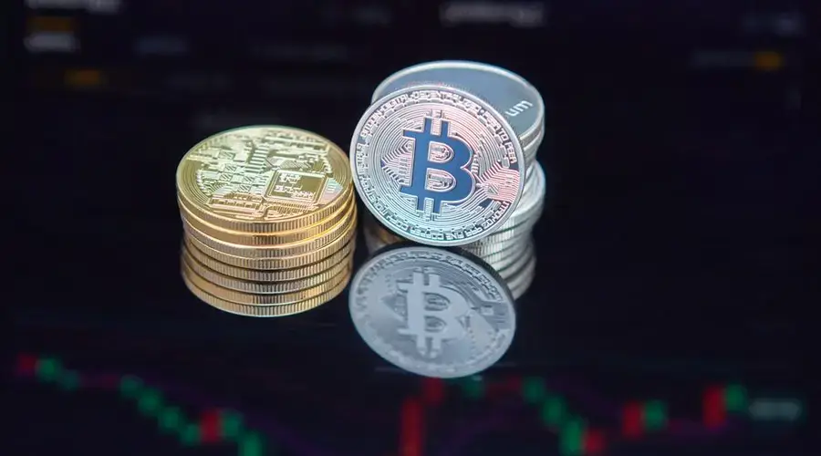 Close-up of bitcoin coins reflecting on a screen with financial market data, highlighting digital currency trend.