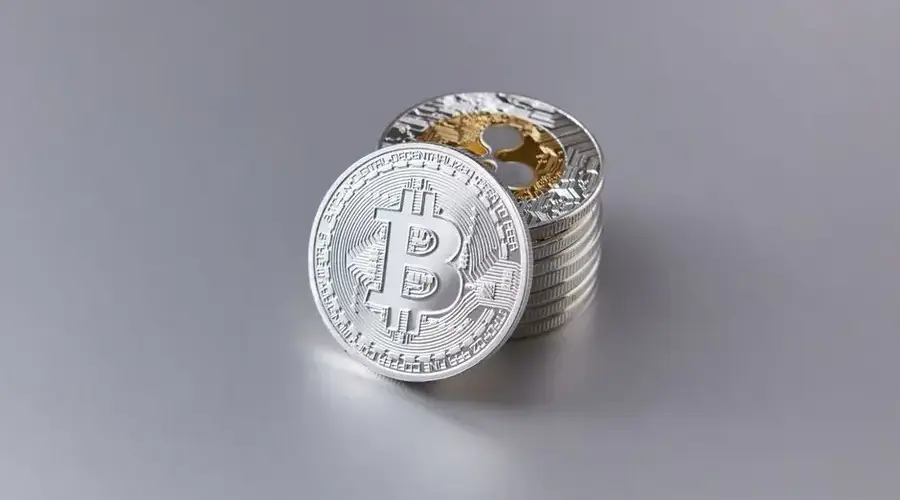 Close-up of shiny Bitcoin cryptocurrency coins with a reflective surface on a gray background.